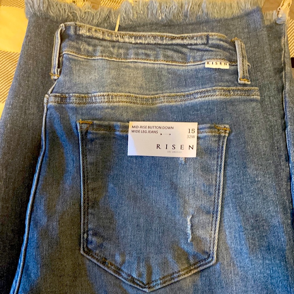 Risen Jeans. Mid-rise. Button-down and wide leg with unfinished hem.